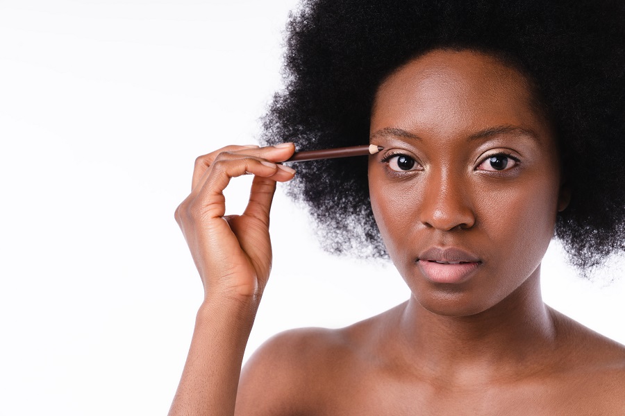 Pretty young afro girl doing make-up isolated over white background