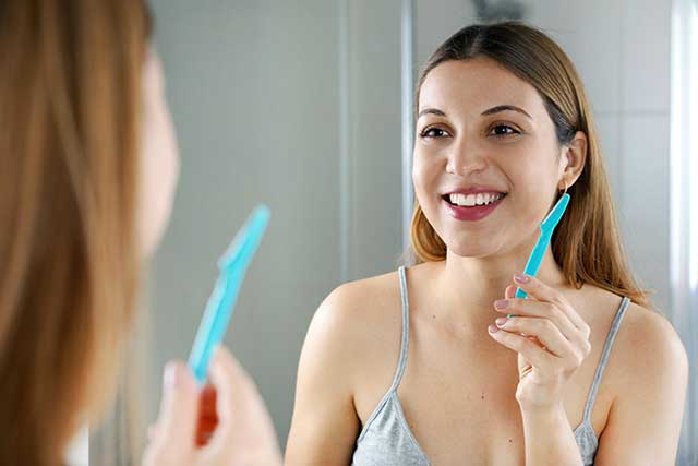 beautiful woman holding razor for facial hair removal
